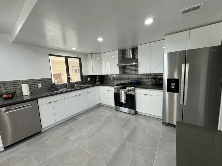 Glossy white kitchen cabinetry and cement-gray countertops in Burbank