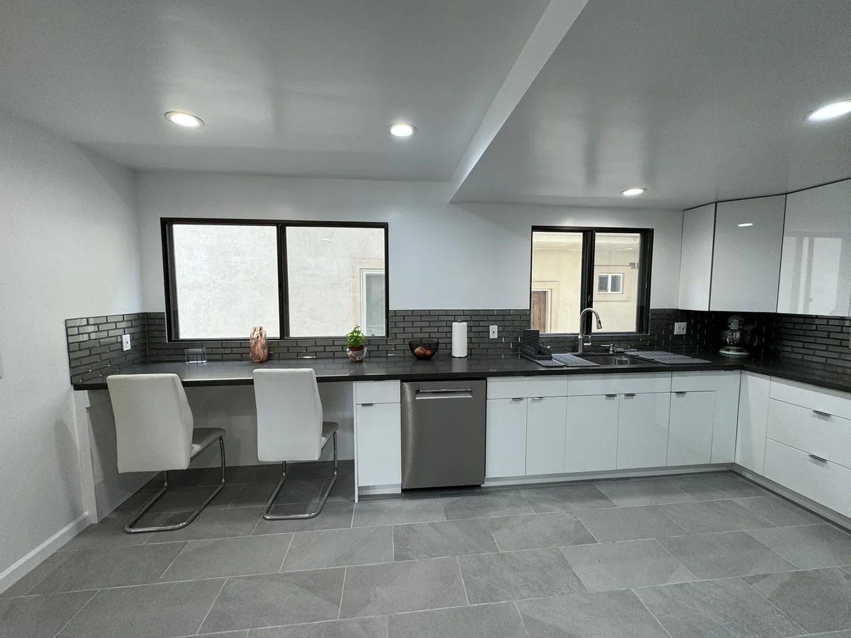 Window-side breakfast seating beside the sink, dishwasher, and white kitchen cabinets