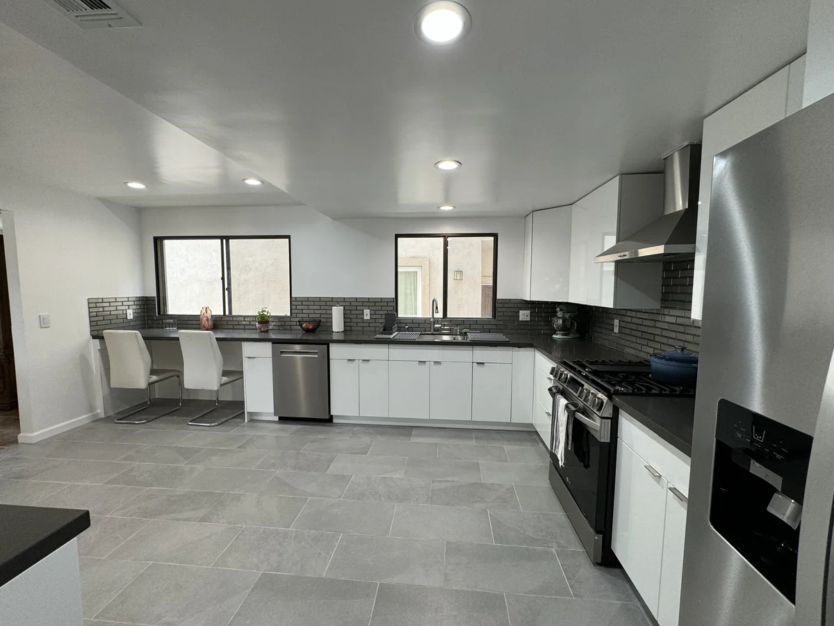 View across the kitchen toward the sink and breakfast counter with a stainless steel range at the right