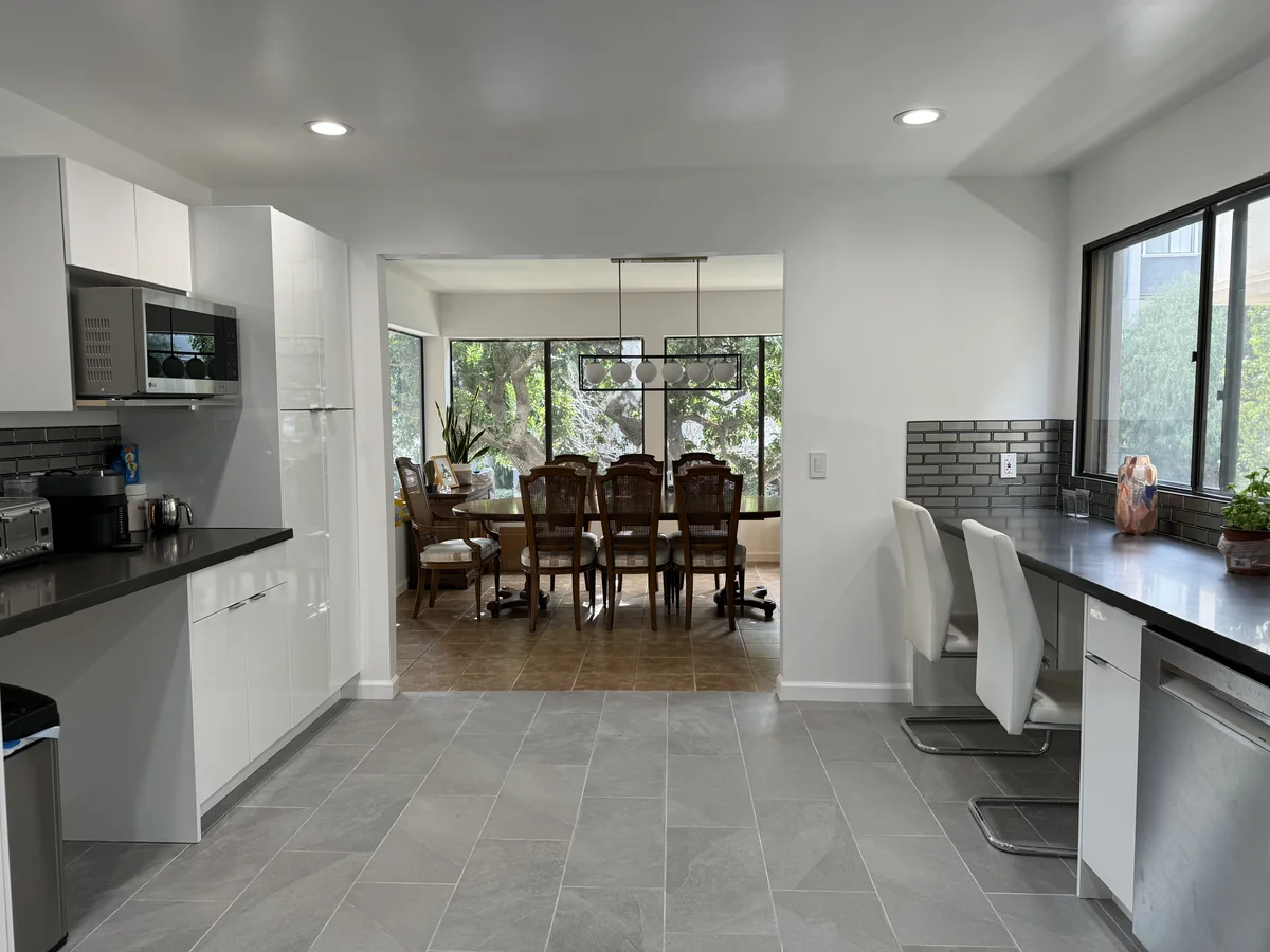 Kitchen breakfast seating beside a window with a dining table and glass doors beyond