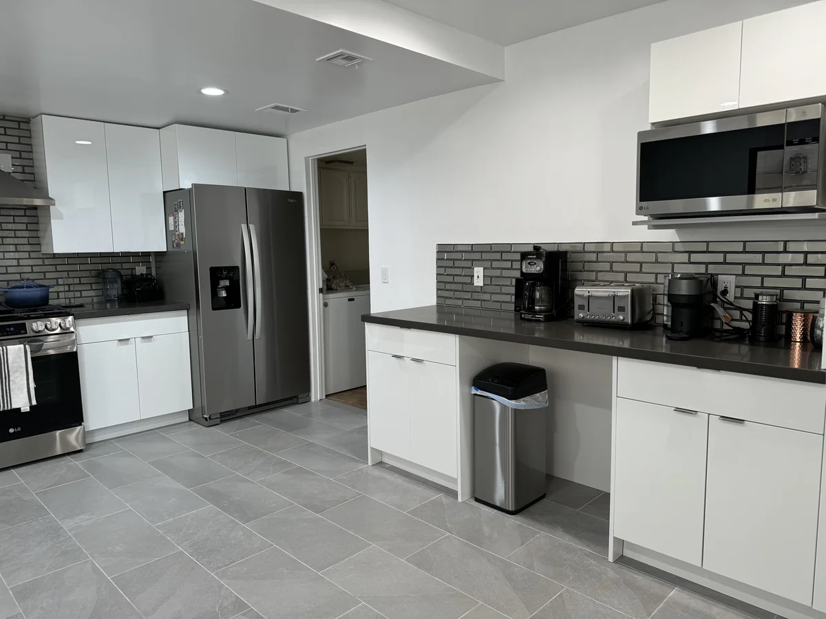 Microwave counter with glossy white drawers and cabinets beside the refrigerator