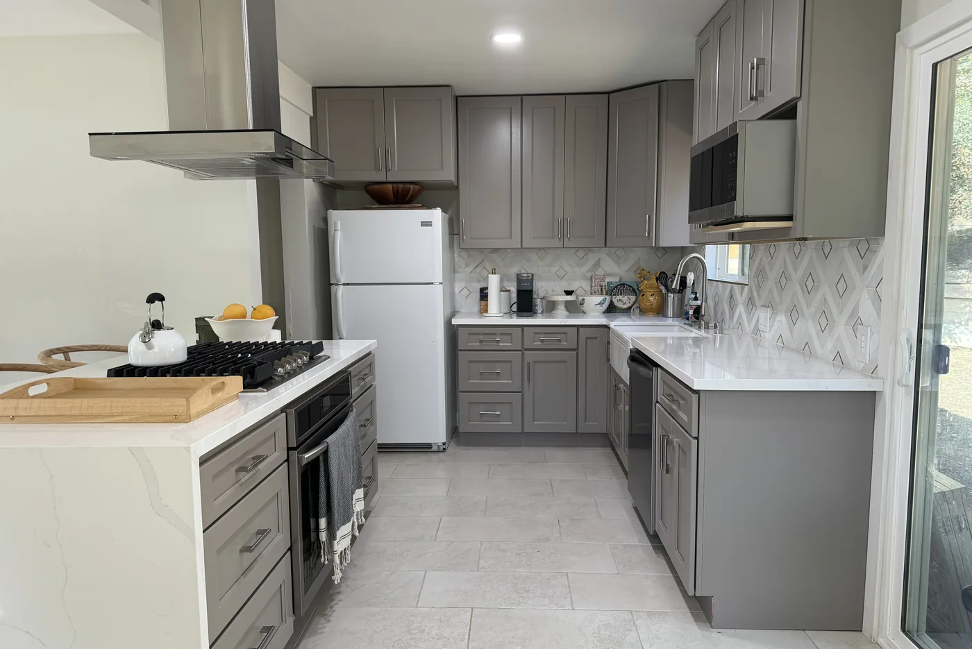 Gray shaker kitchen in Sunland with a patterned backsplash, light countertops, and a peninsula