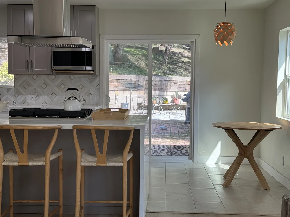 Breakfast bar with wooden stools, gray cabinetry, and pendant lighting beside the dining area
