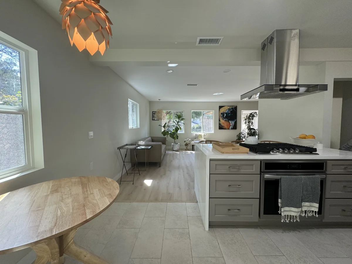 Kitchen range and stainless steel hood beside the dining table and open living area