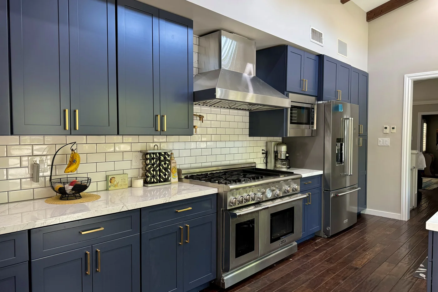 Indigo blue kitchen in Pasadena with bronze hardware, white quartz countertops, and a stainless steel range hood