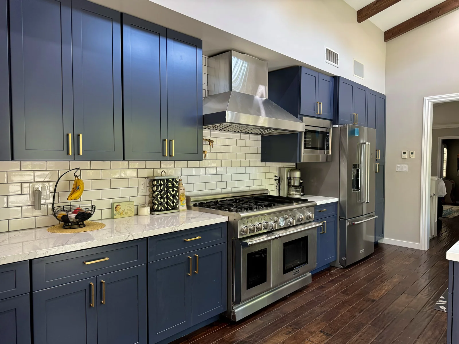 Indigo blue kitchen in Pasadena with a stainless steel range, white quartz counters, and bronze hardware