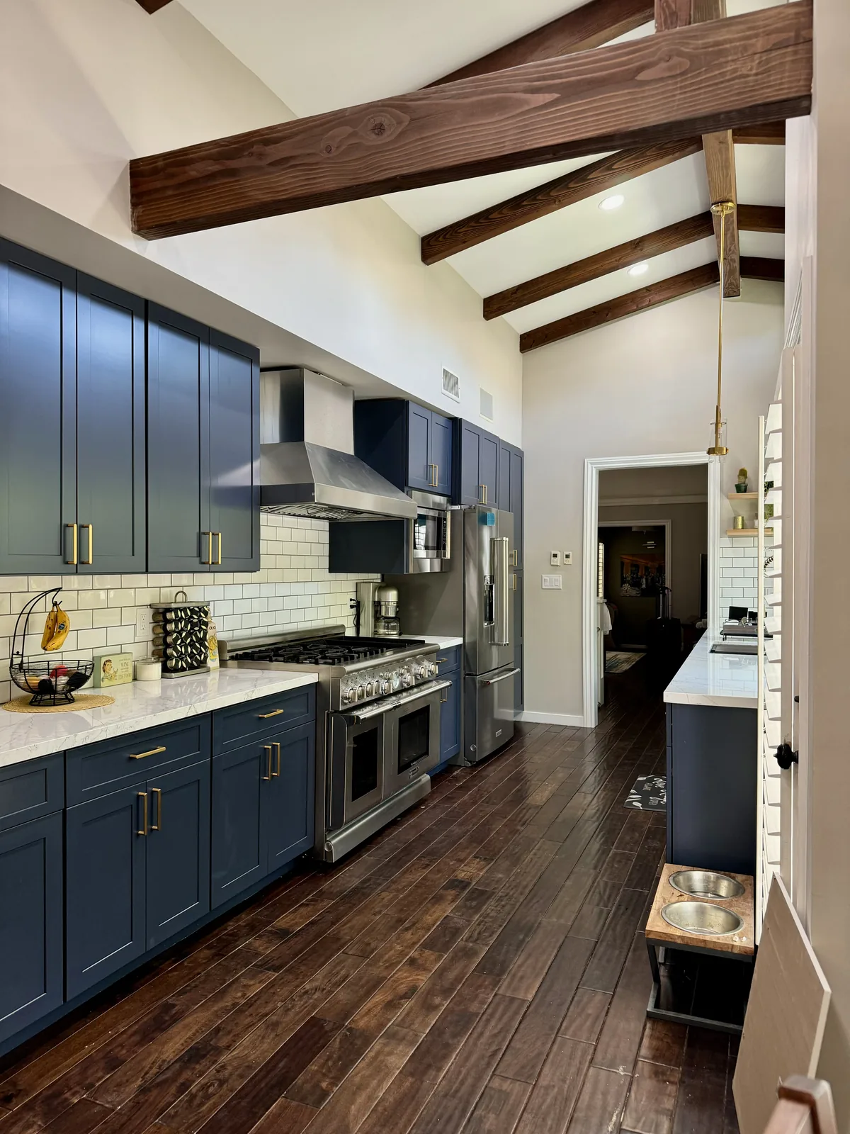 Indigo blue cabinetry and white quartz countertops beneath exposed wood ceiling beams