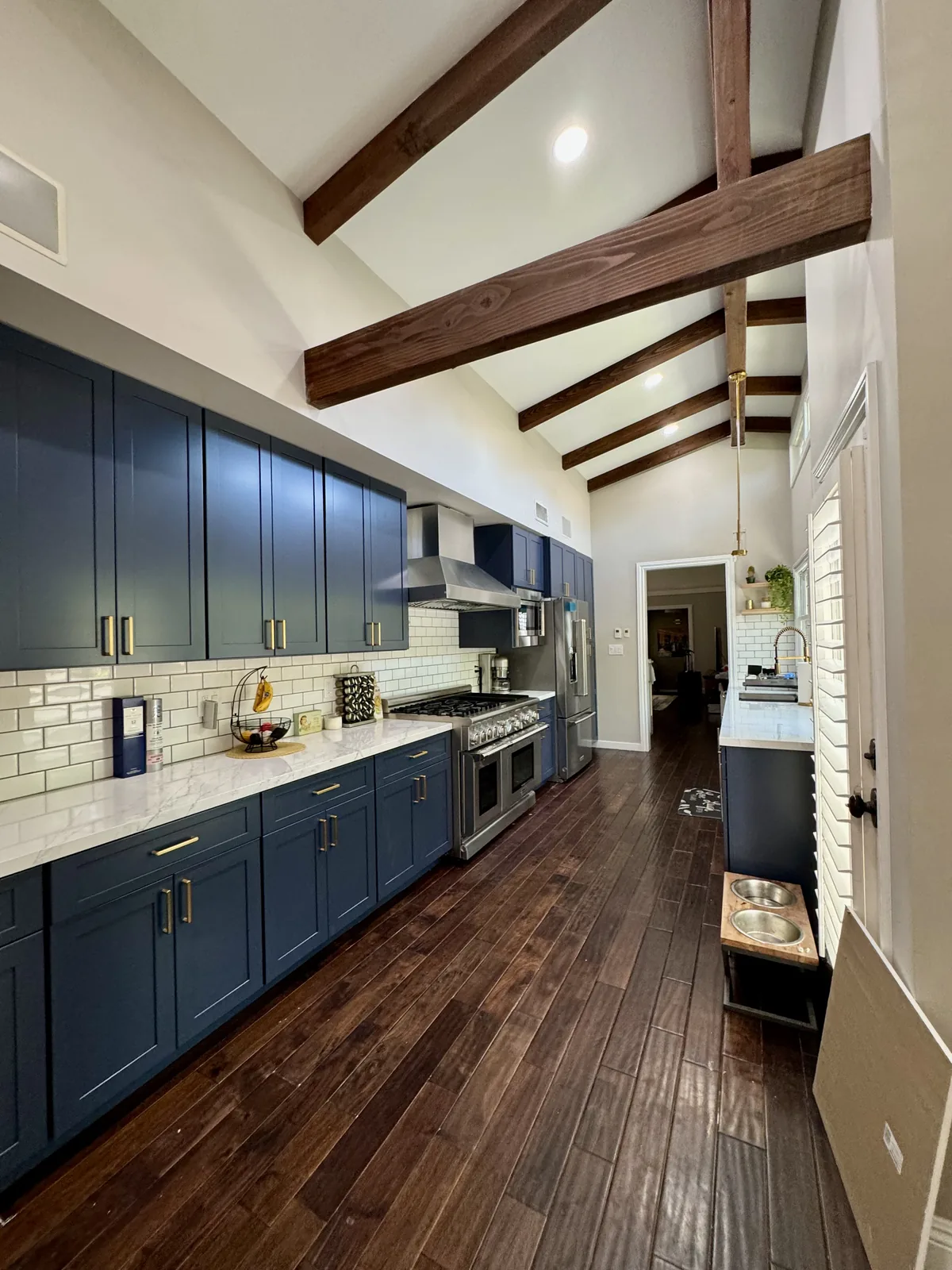 Long view of the Pasadena kitchen with blue cabinets, bronze hardware, and wood flooring