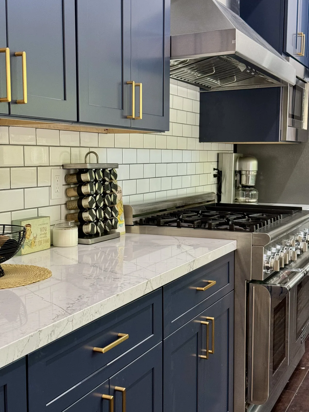 Close-up of bronze cabinet handles, veined quartz countertop, and white tile backsplash