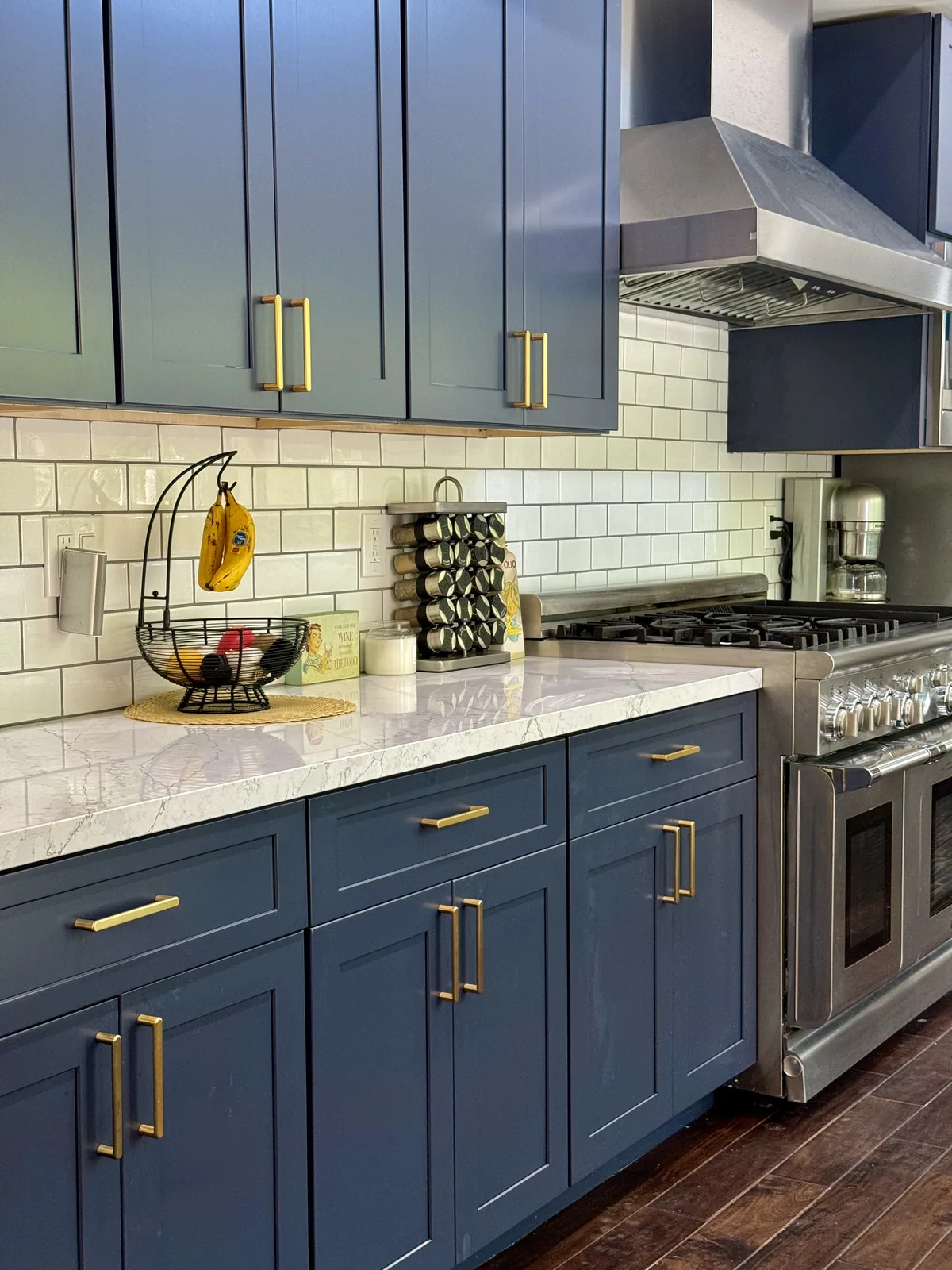 Indigo blue drawers and upper cabinets with bronze hardware beside the range