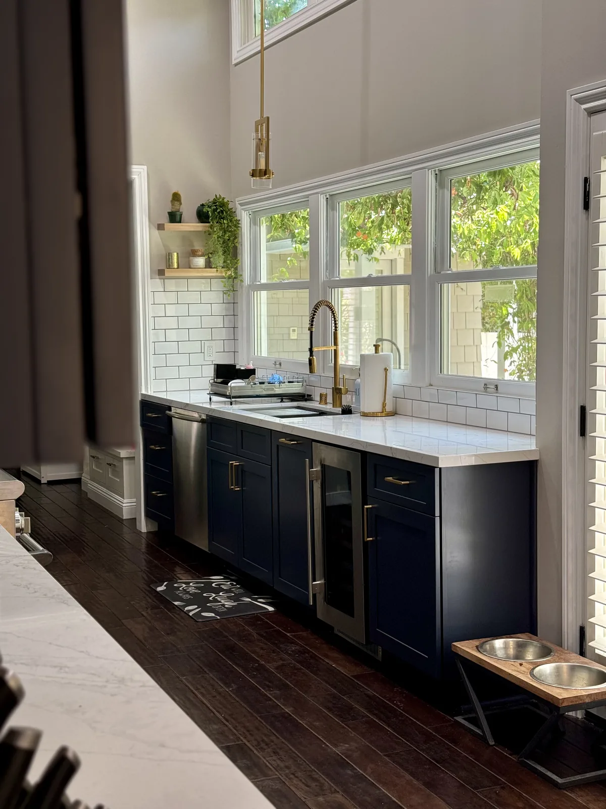 Sink, faucet, and blue cabinetry beneath the kitchen windows