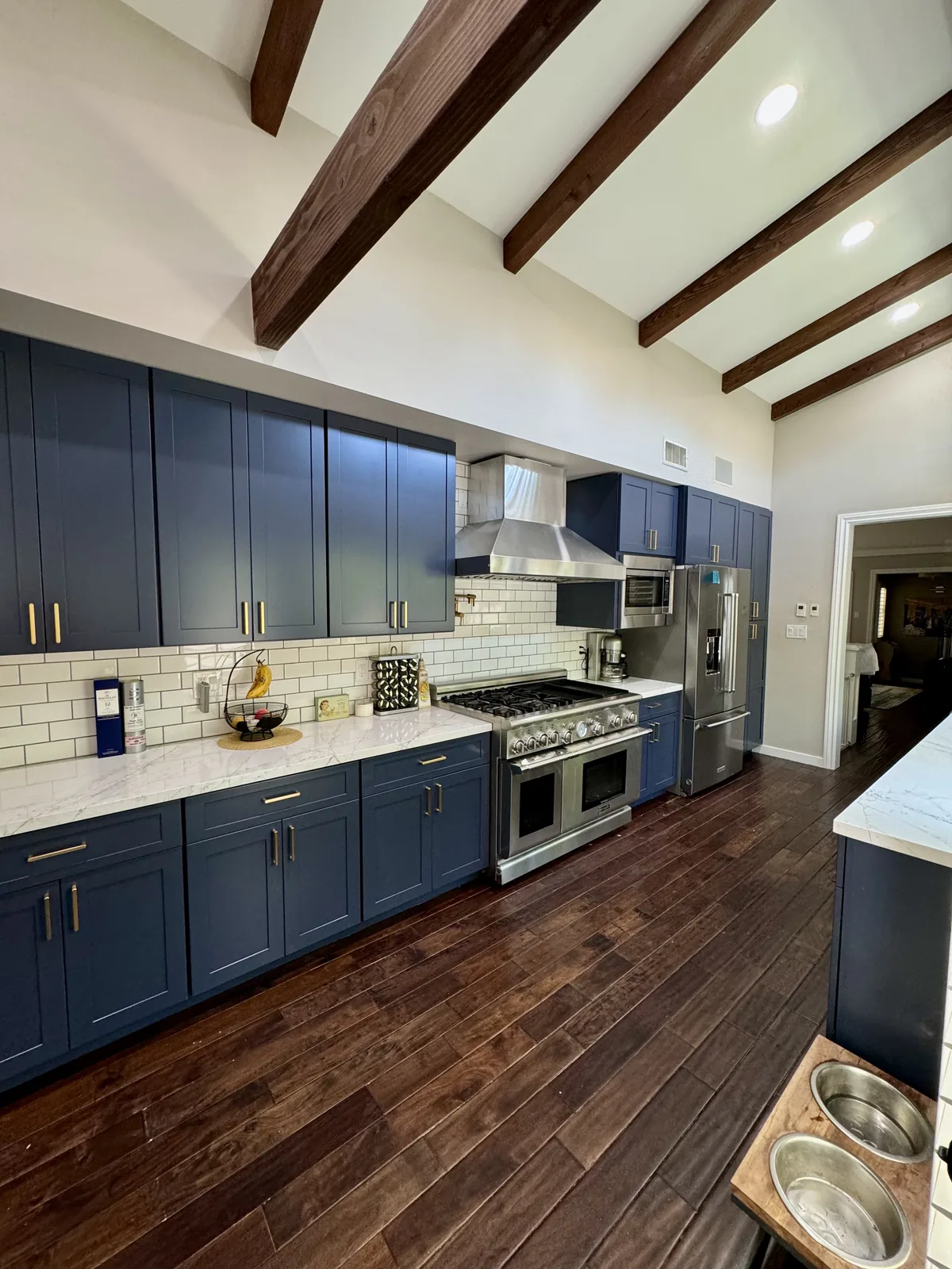 White quartz countertop and blue cabinets under exposed wood beams in Pasadena