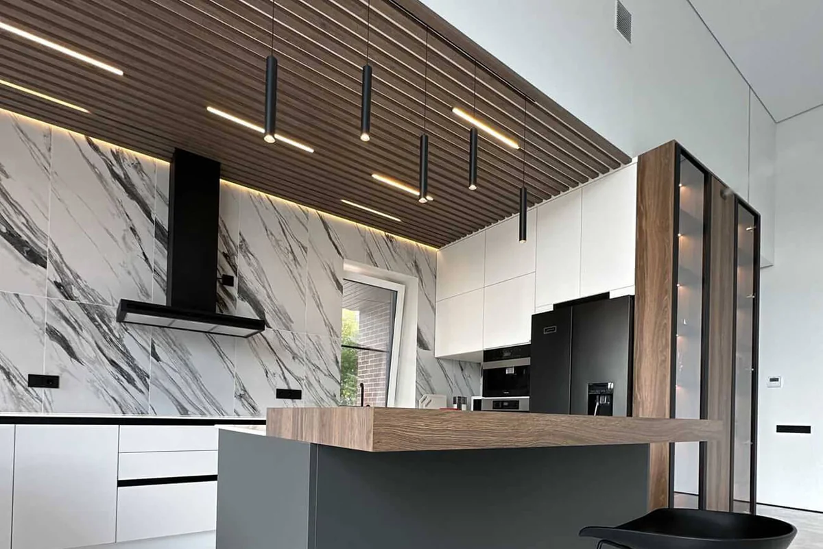 Ultra-modern kitchen with a veined porcelain backsplash, wood ceiling paneling, and pendant lights above the island