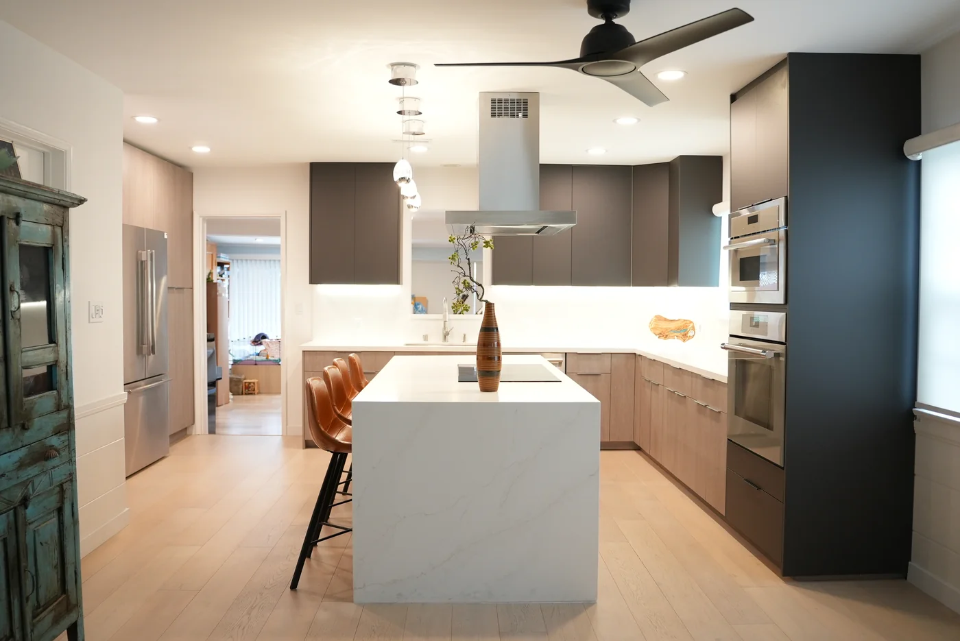 Completed Van Nuys kitchen with anthracite and wood-tone cabinets, a white waterfall island, pendant lights, and an island hood