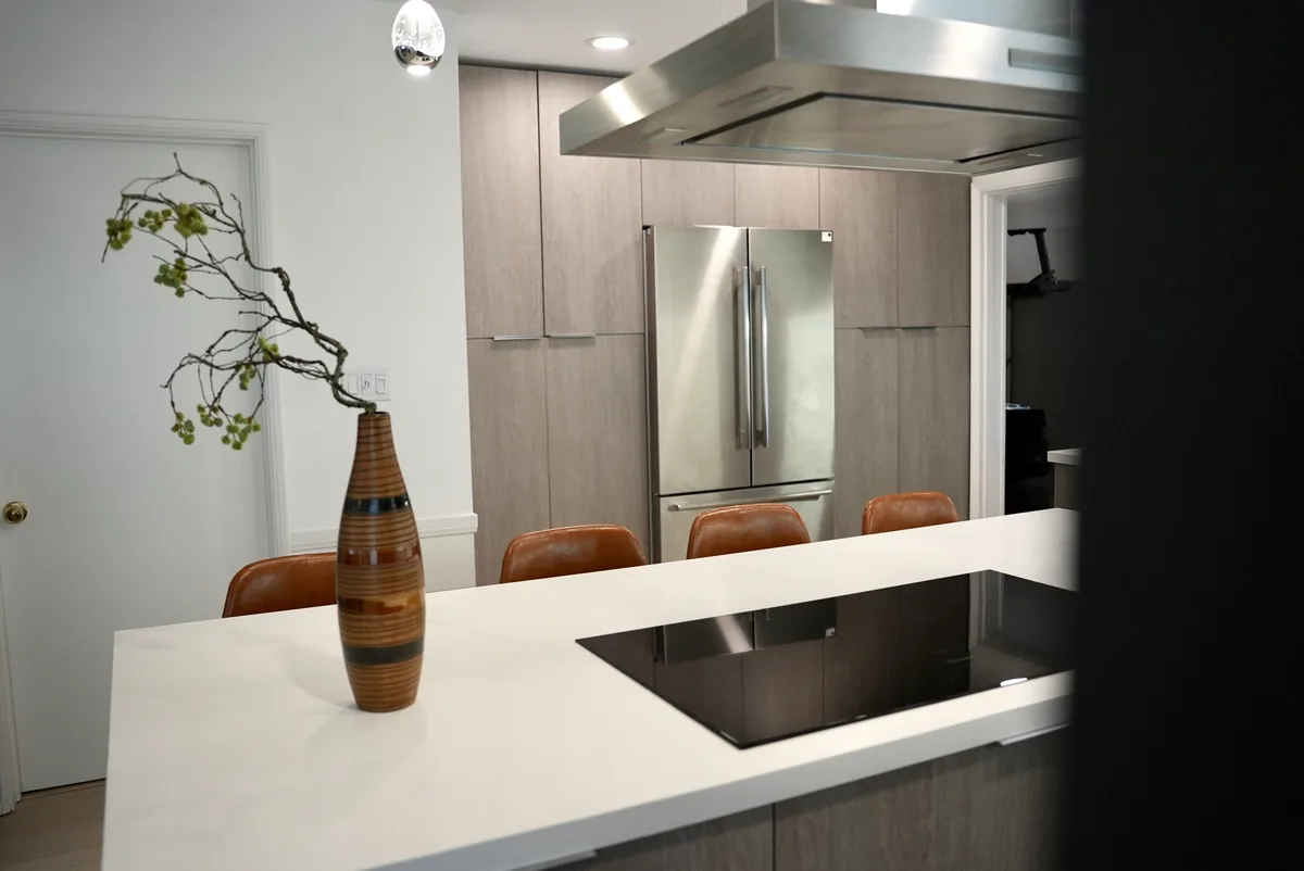 White island with an integrated black cooktop and a view of the refrigerator