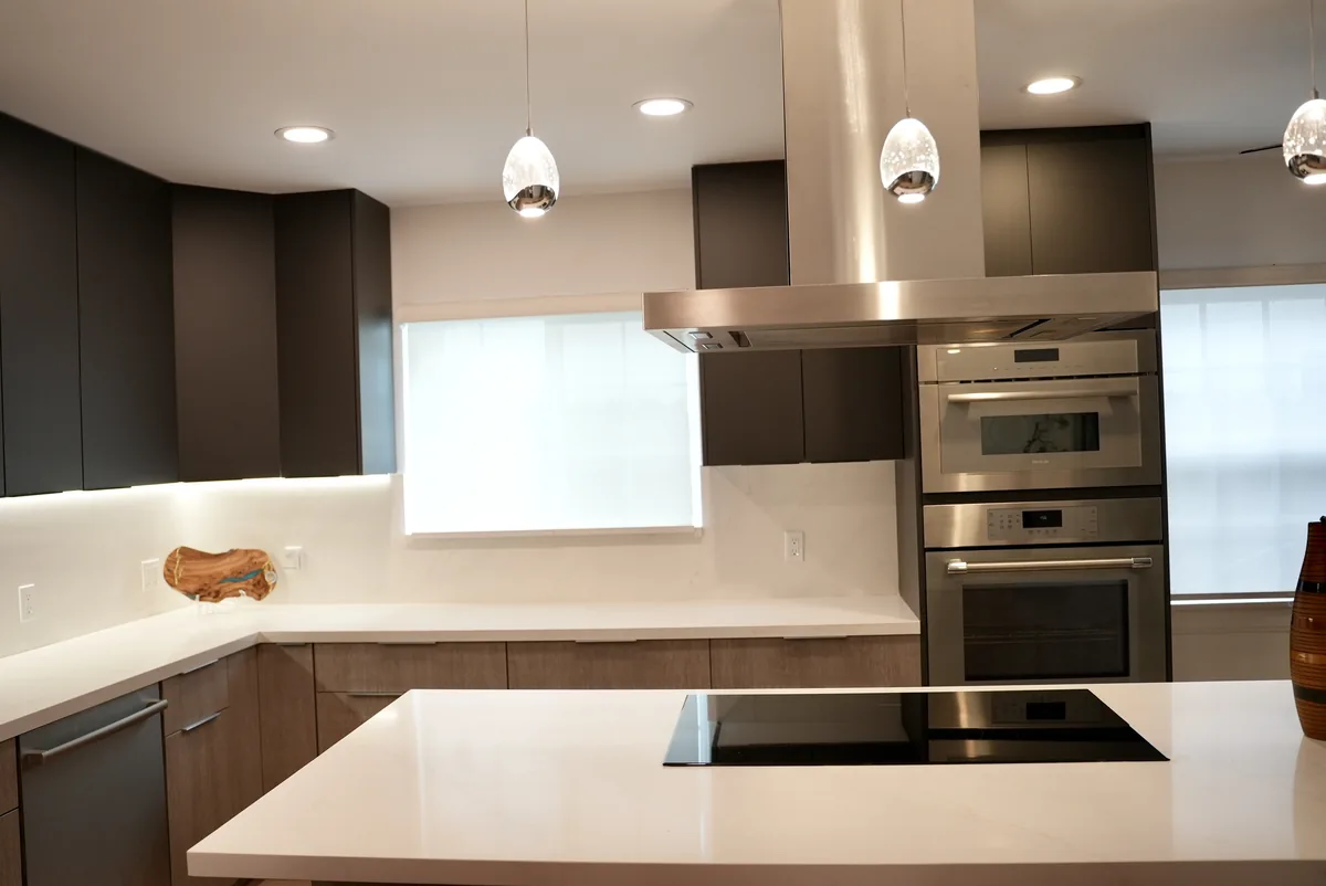 Pendant lights above the island with anthracite cabinets and built-in ovens behind