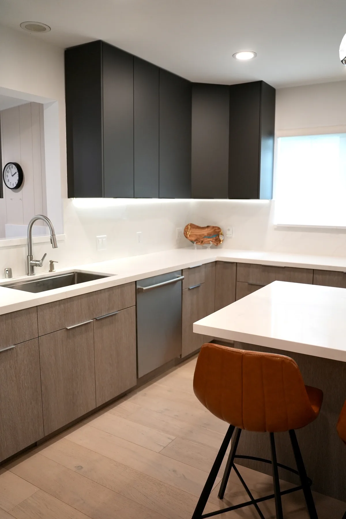Kitchen sink and faucet with wood-tone lower cabinets and white countertops