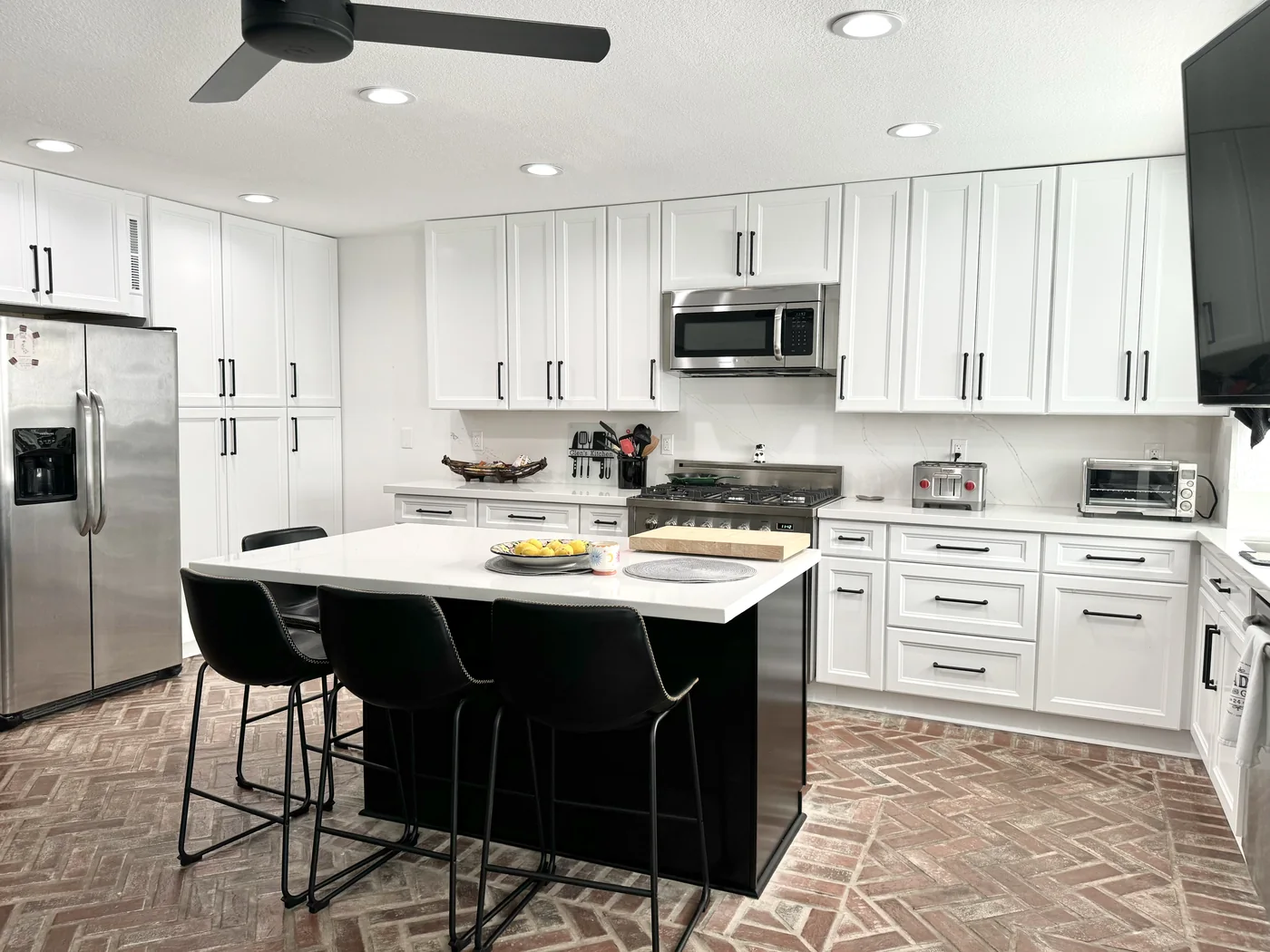 White shaker kitchen in Woodland Hills with an espresso island, white countertops, and black bar stools