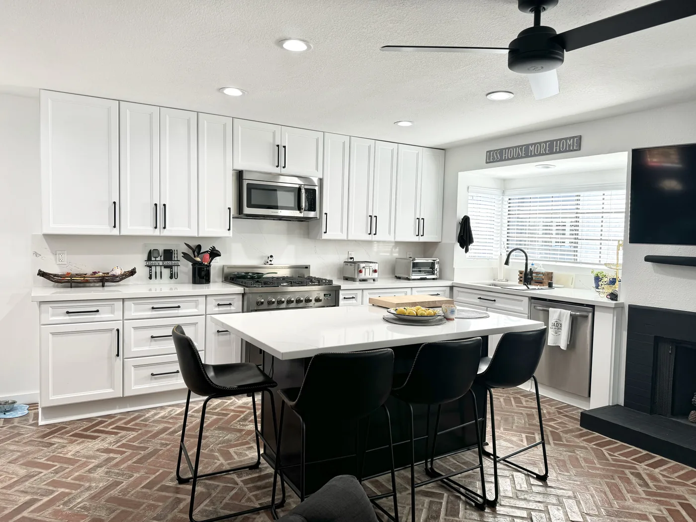 Wide view of white kitchen cabinets, a dark espresso island, and the window above the sink