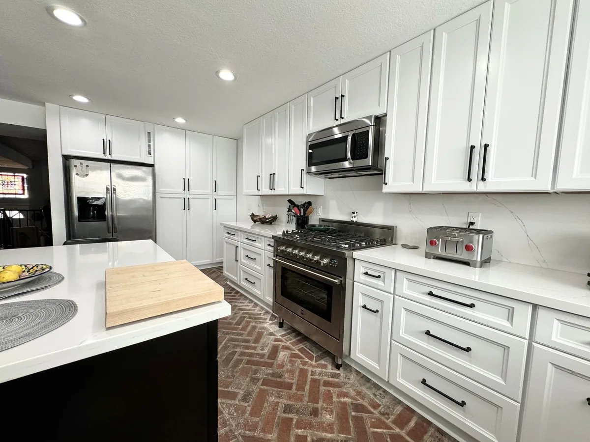 White shaker cabinets and drawers around a stainless steel range with a microwave above