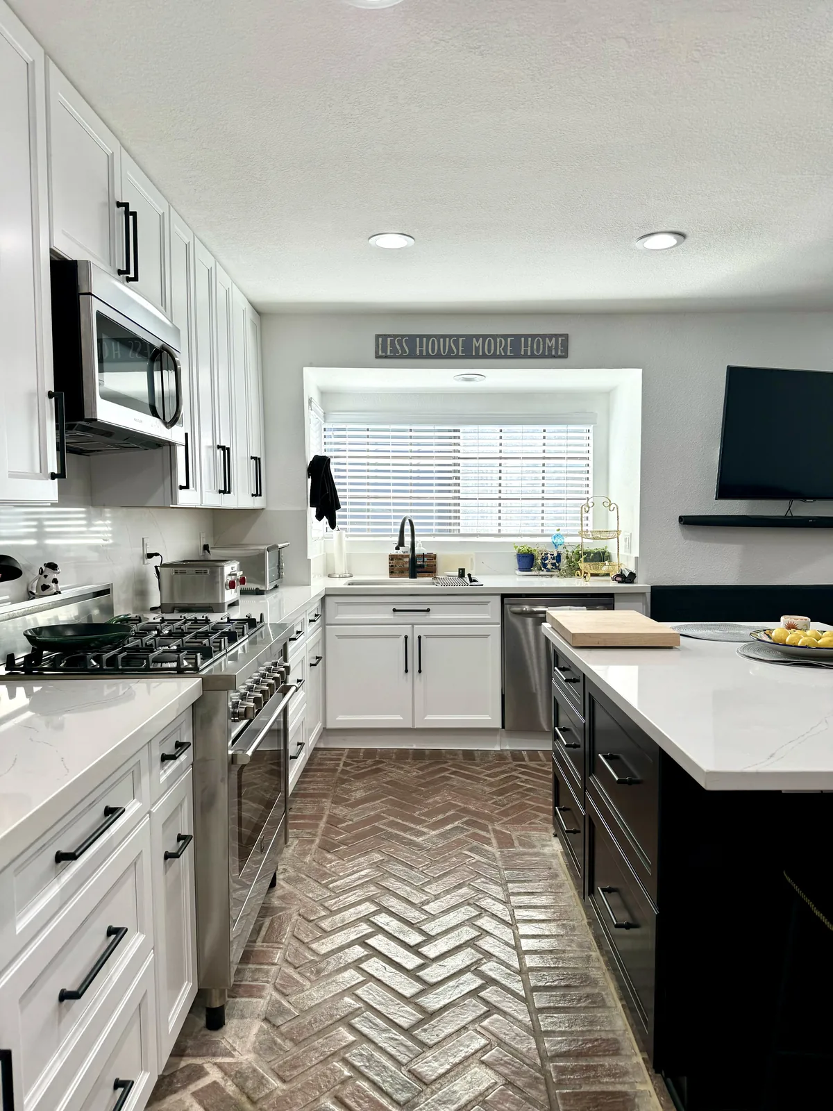 Kitchen aisle between white perimeter cabinets and the espresso island with herringbone-pattern flooring