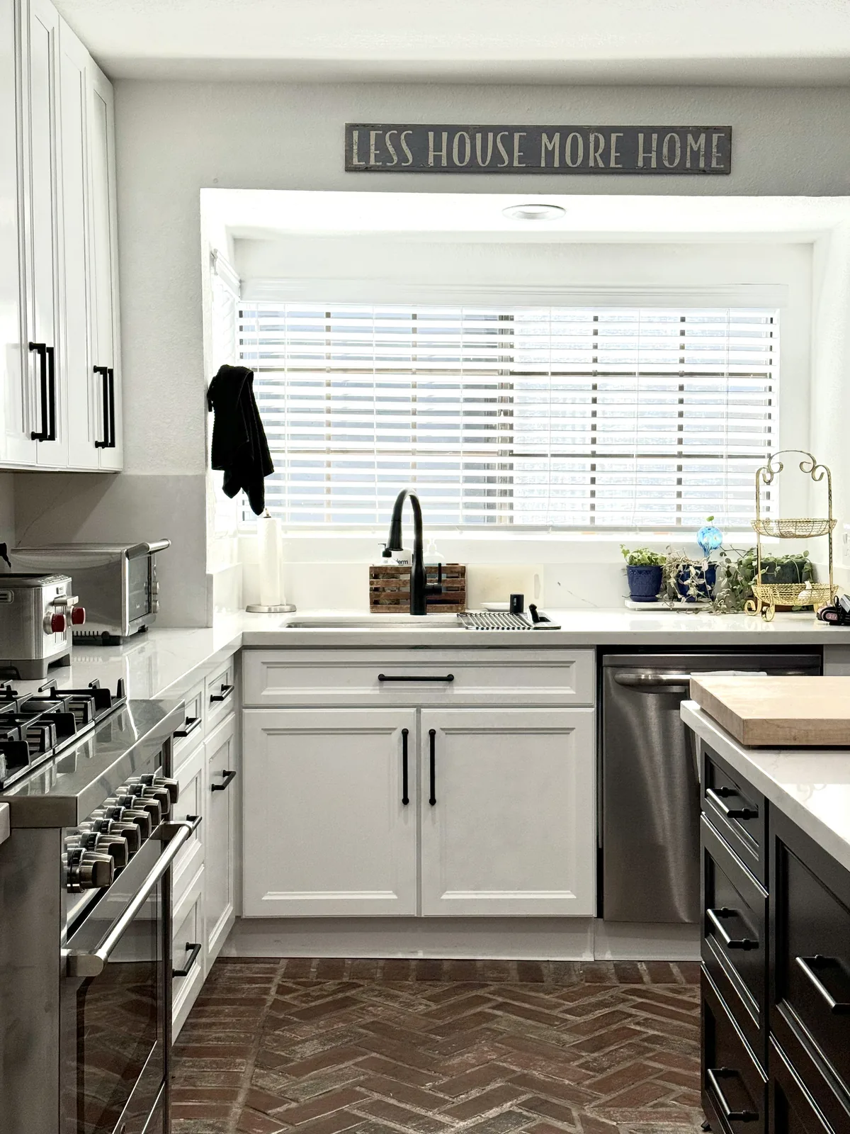 White sink cabinet and dark faucet beneath the kitchen window