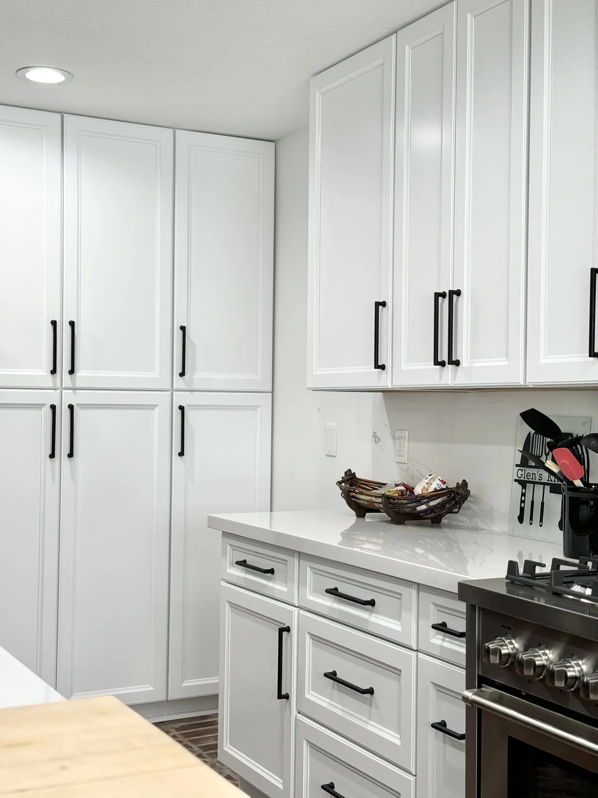 Tall white shaker pantry cabinets beside drawers and the cooking area