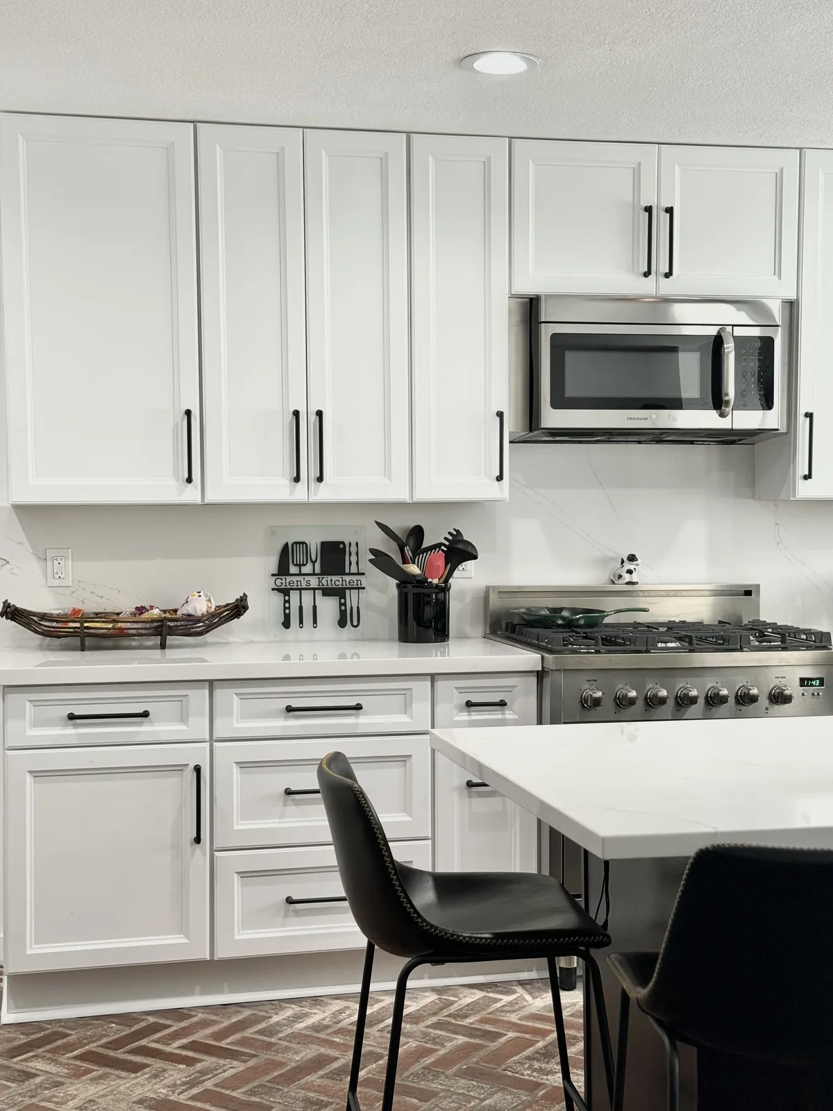 White shaker cabinets, stainless steel microwave, and range behind the island countertop