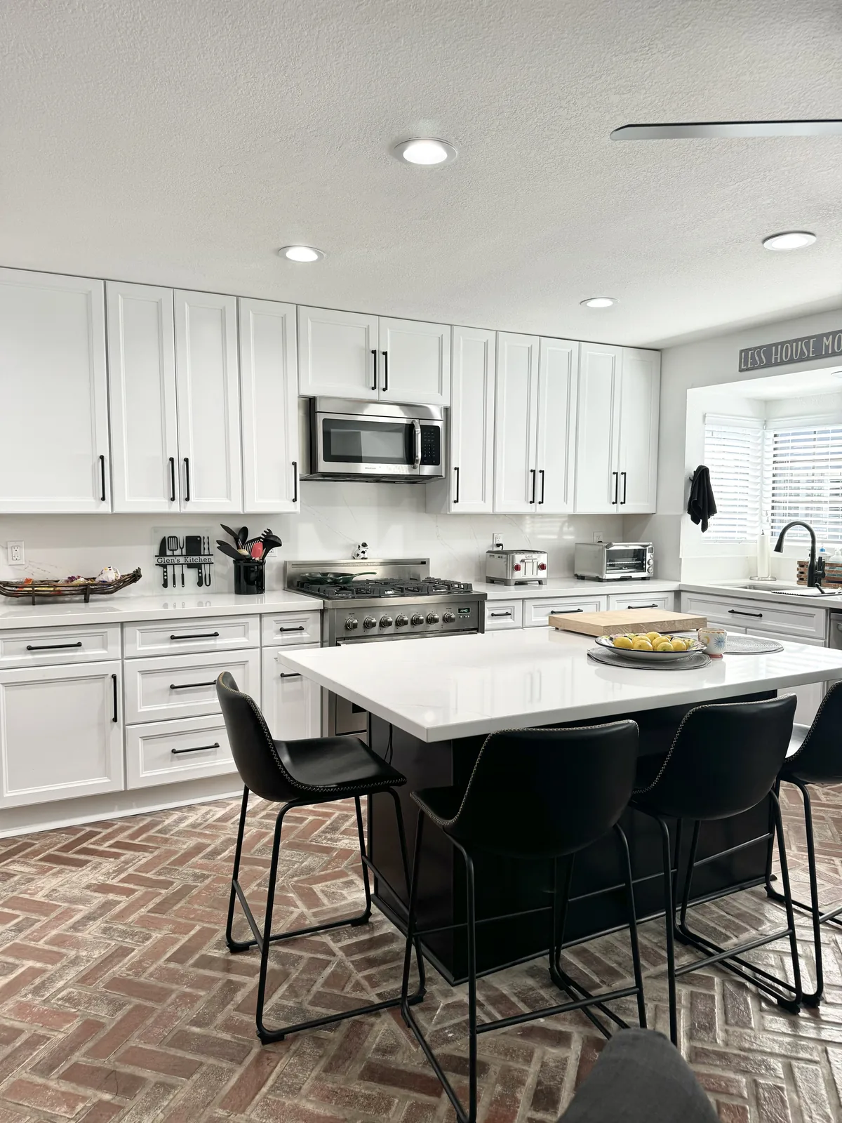 Espresso island with black bar stools and white cabinetry across the kitchen