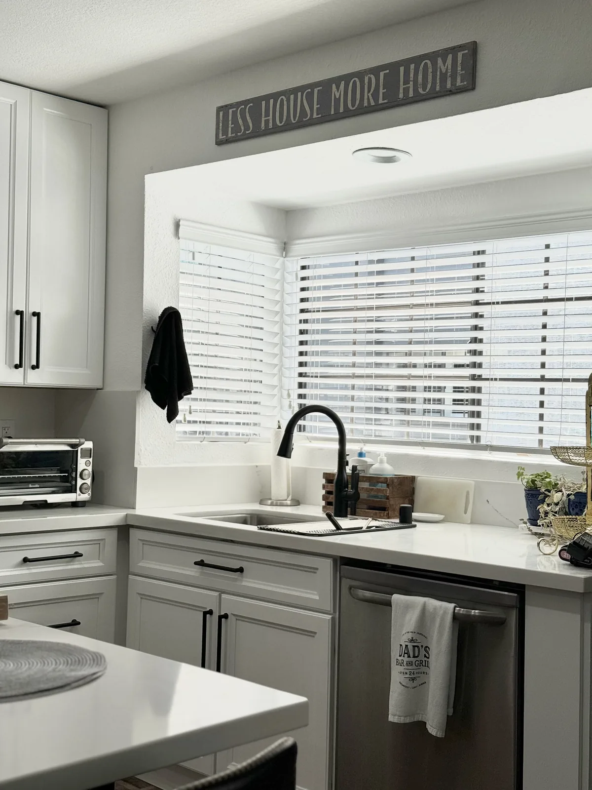Dark faucet and sink beneath the window with a stainless steel dishwasher alongside