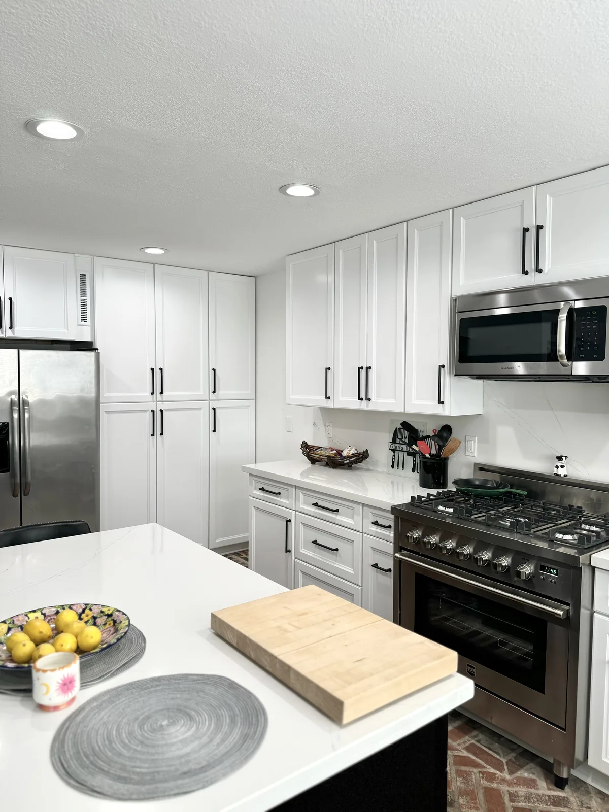 View across the island countertop toward white shaker drawers and the stainless steel range