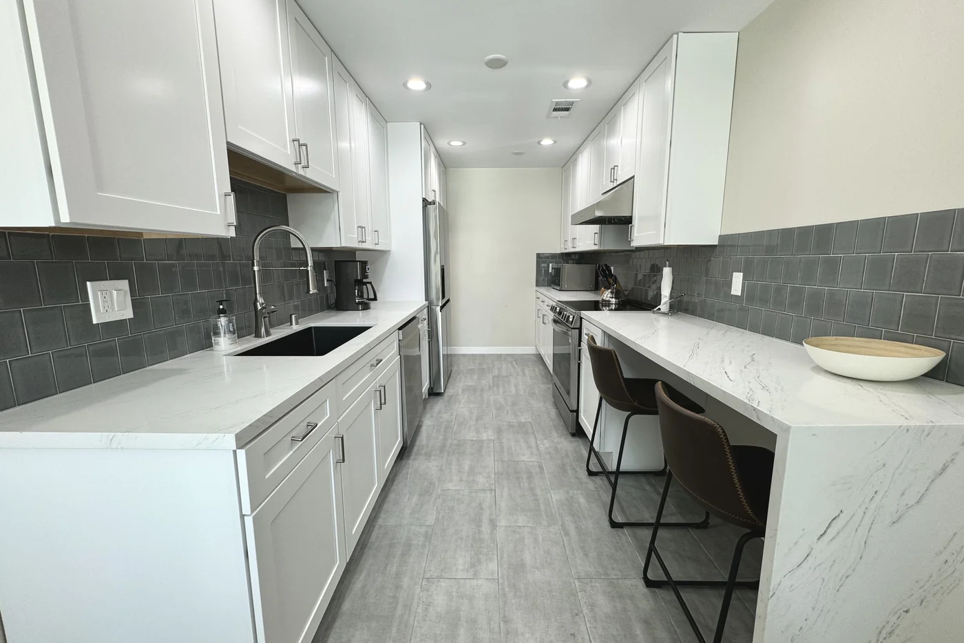 White shaker galley kitchen in Glendale with a Calacatta quartz countertop and dark tile backsplash