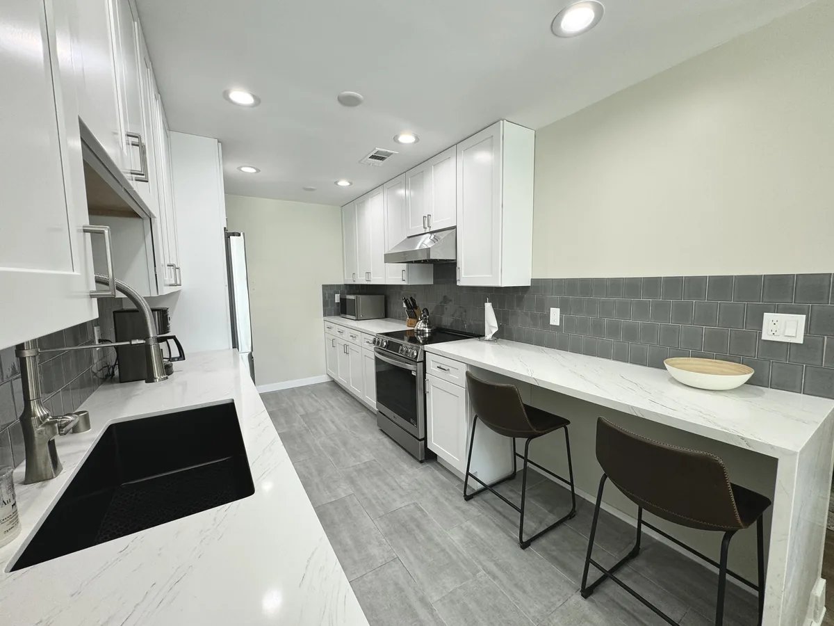 Galley kitchen layout with the sink on one side and the range and breakfast bar on the other